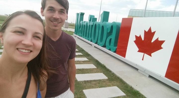 Vee and me standing in front of the Manitoba Welcome sign